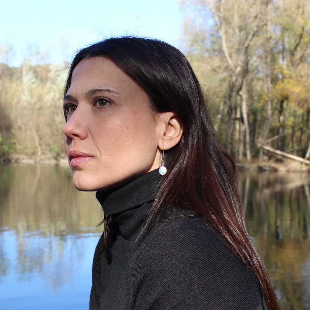 Model by river looking away wearing bohemian boho chic Haawy earrings made of sterling silver featuring freshwater pearls