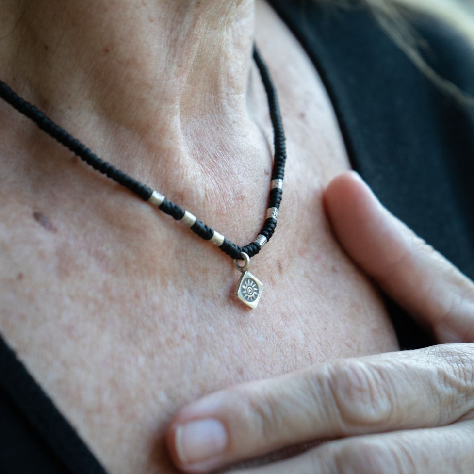 Model wearing fossil charm bohemian boho chic necklace made of sterling silver and waxed cotton