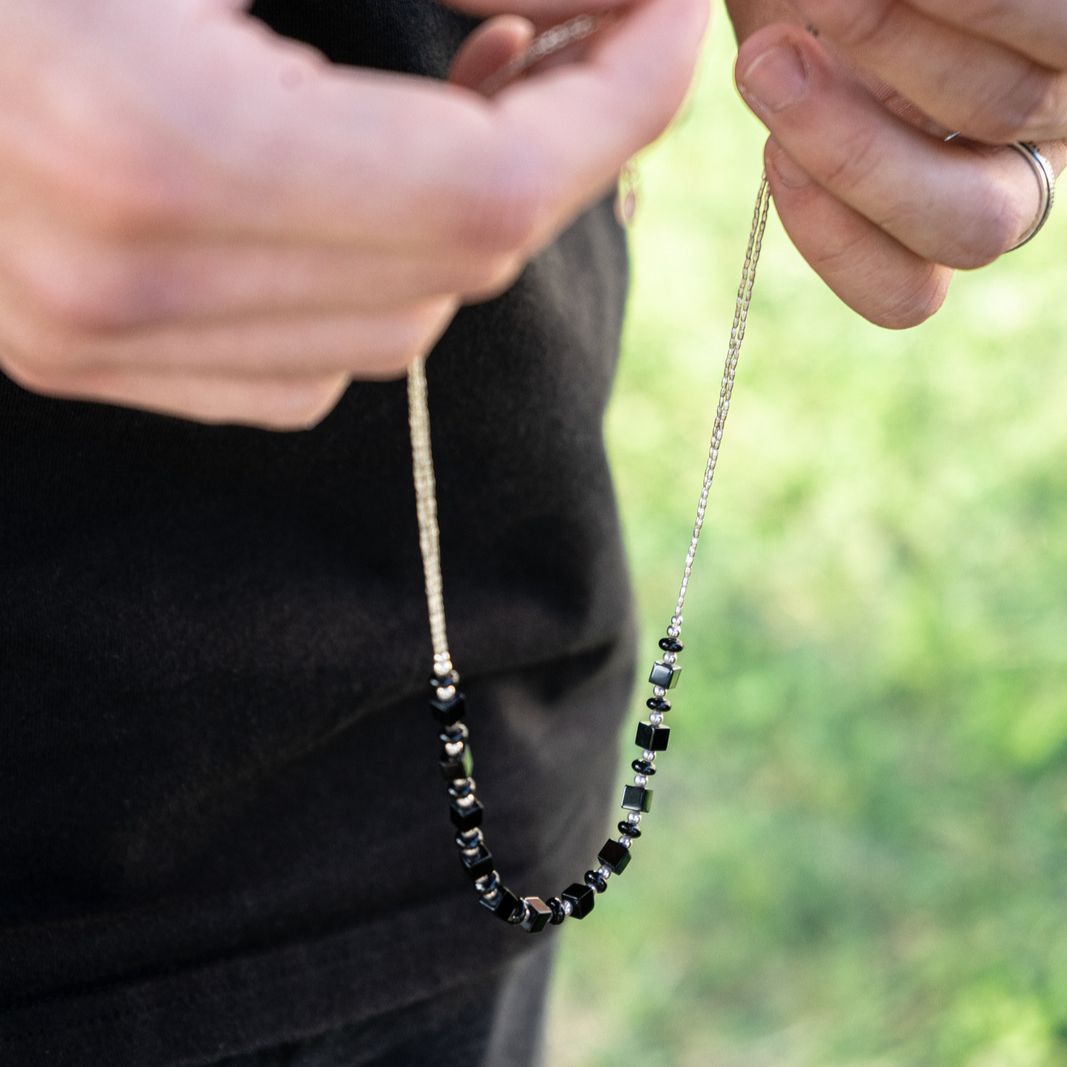 Male model holding boho chic bohemian necklace made of sterling silver and black onyx gemstones beads