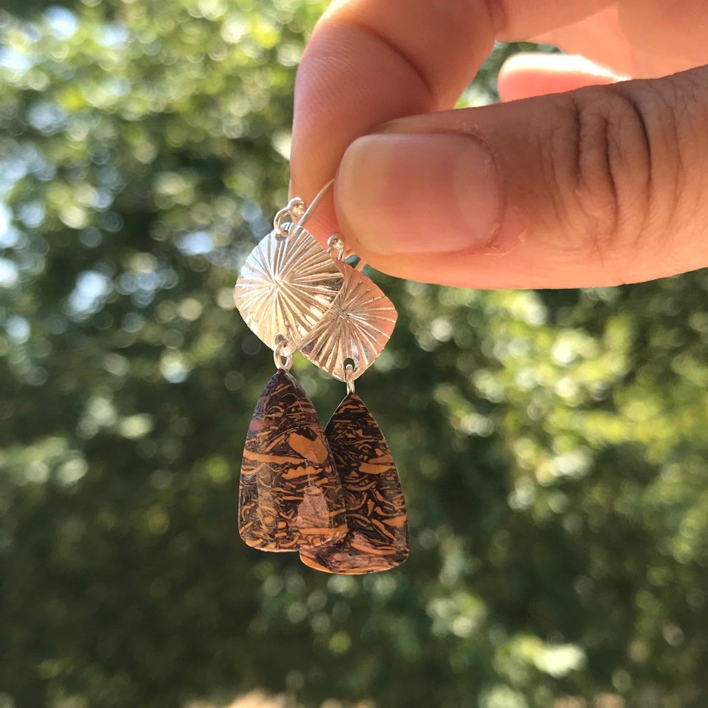 Holding handmade one-of-a-kind coquina jasper gemstone boho chic earrings made of sterling silver