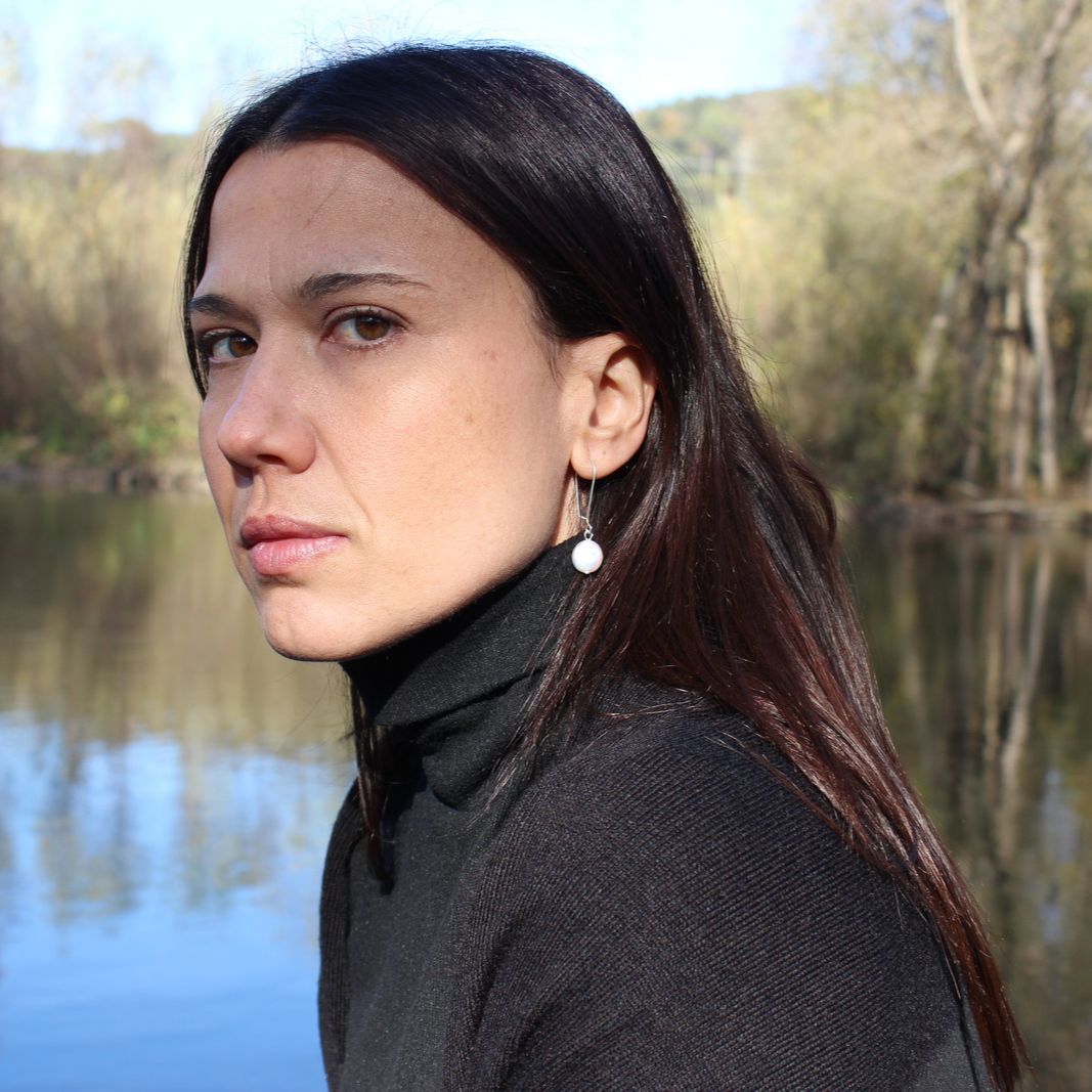 Model by river looking at camera wearing bohemian boho chic Haawy earrings made of sterling silver featuring freshwater pearls