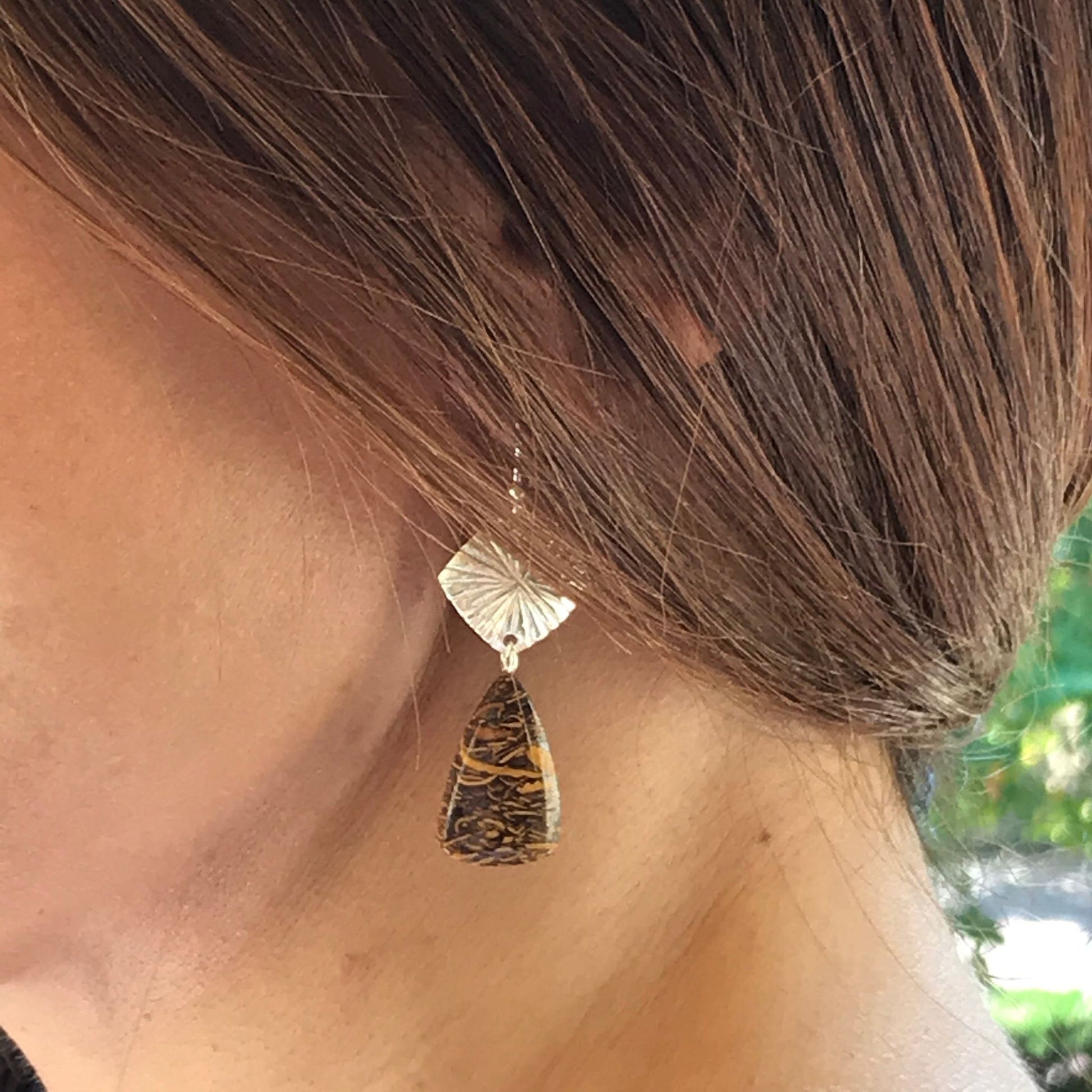 Closeup of model wearing handmade one-of-a-kind coquina jasper gemstone boho chic earrings made of sterling silver