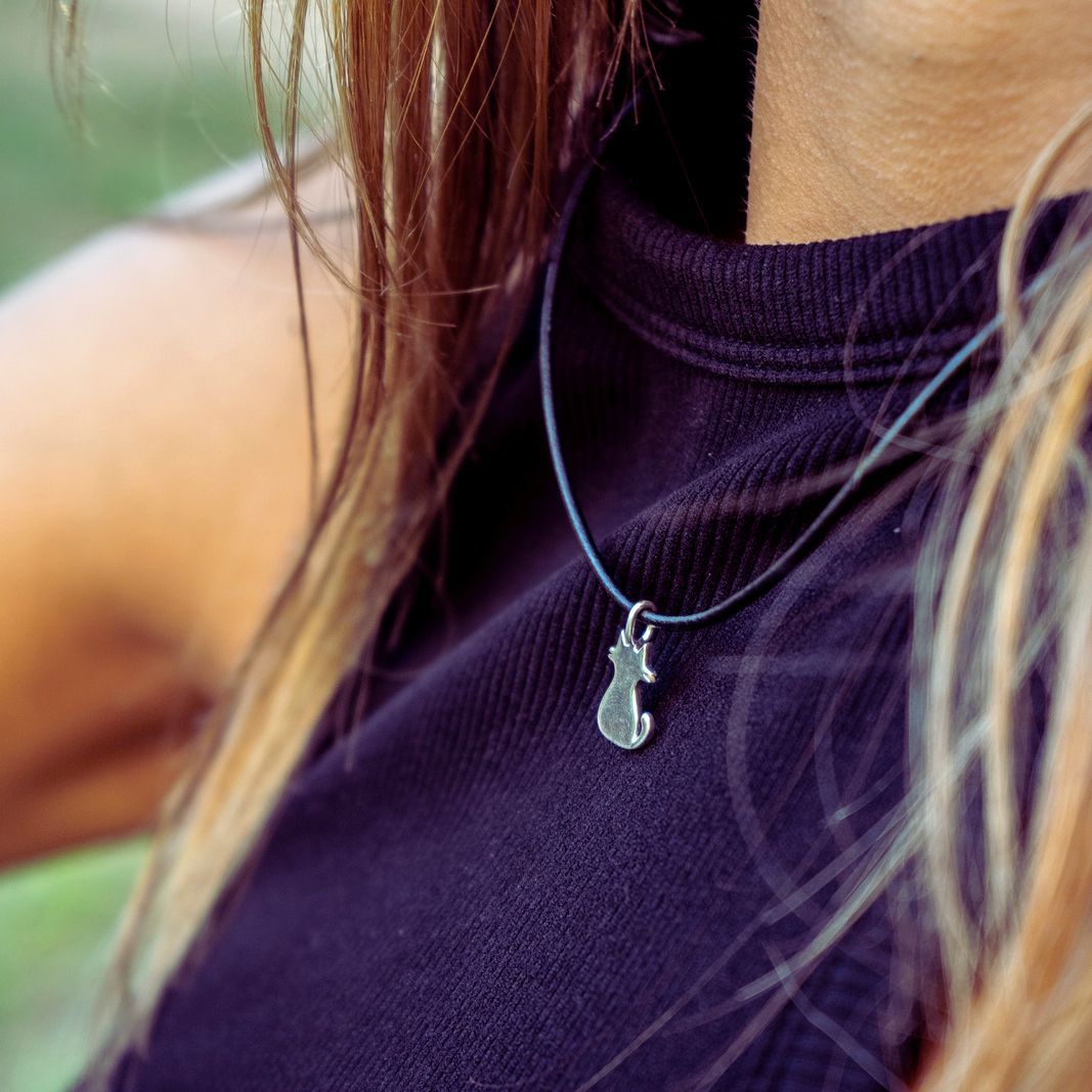 Closeup of model wearing sterling silver boho chic pendant featuring a cat